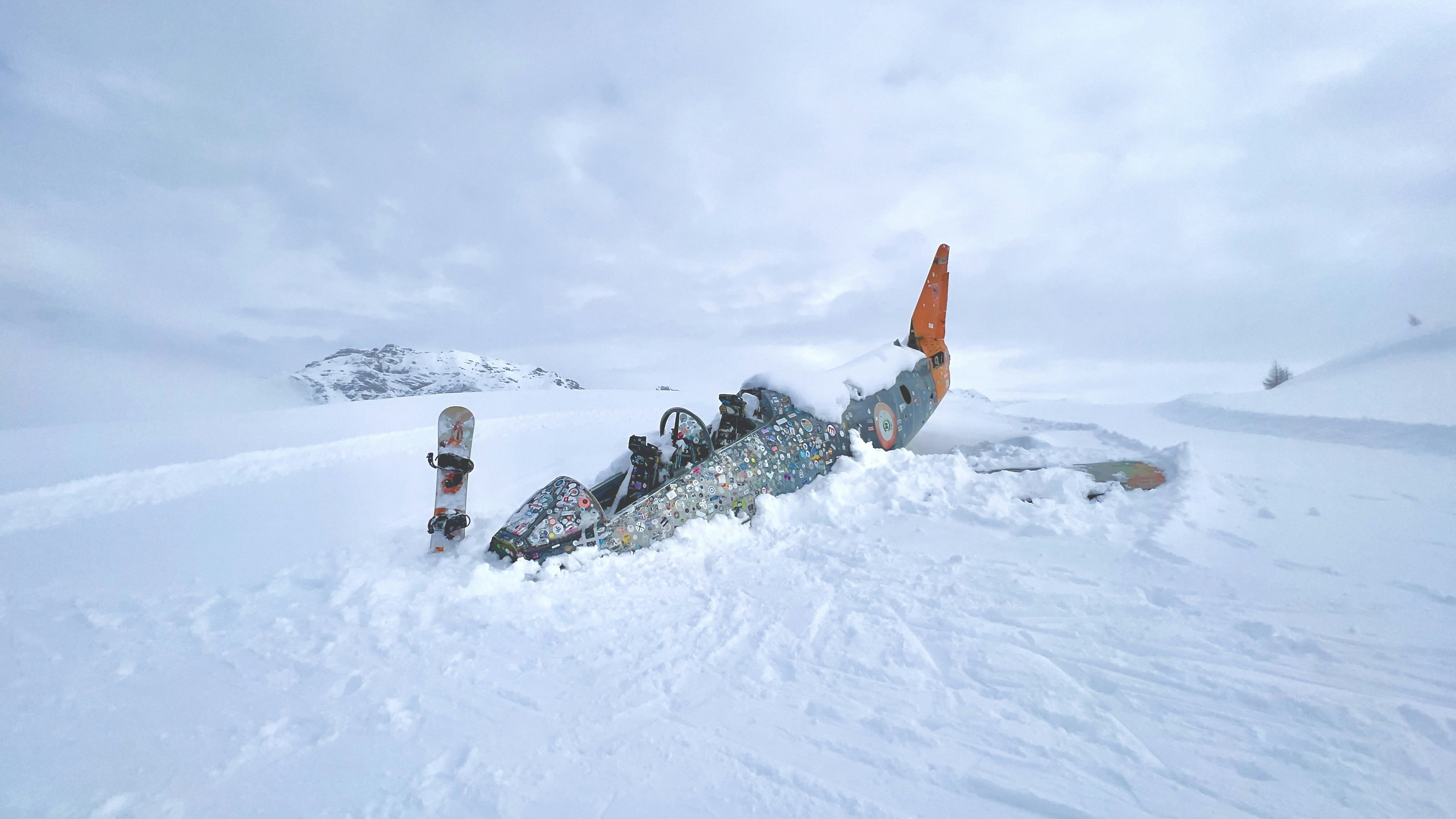 uma pessoa deitada na neve com uma prancha de snowboard