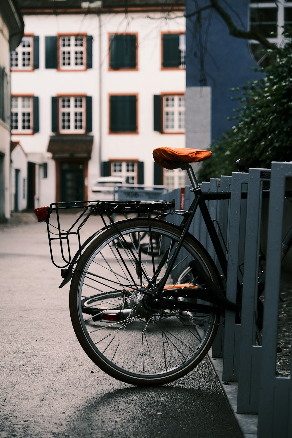 a bicycle parked next to a fence in front of a building