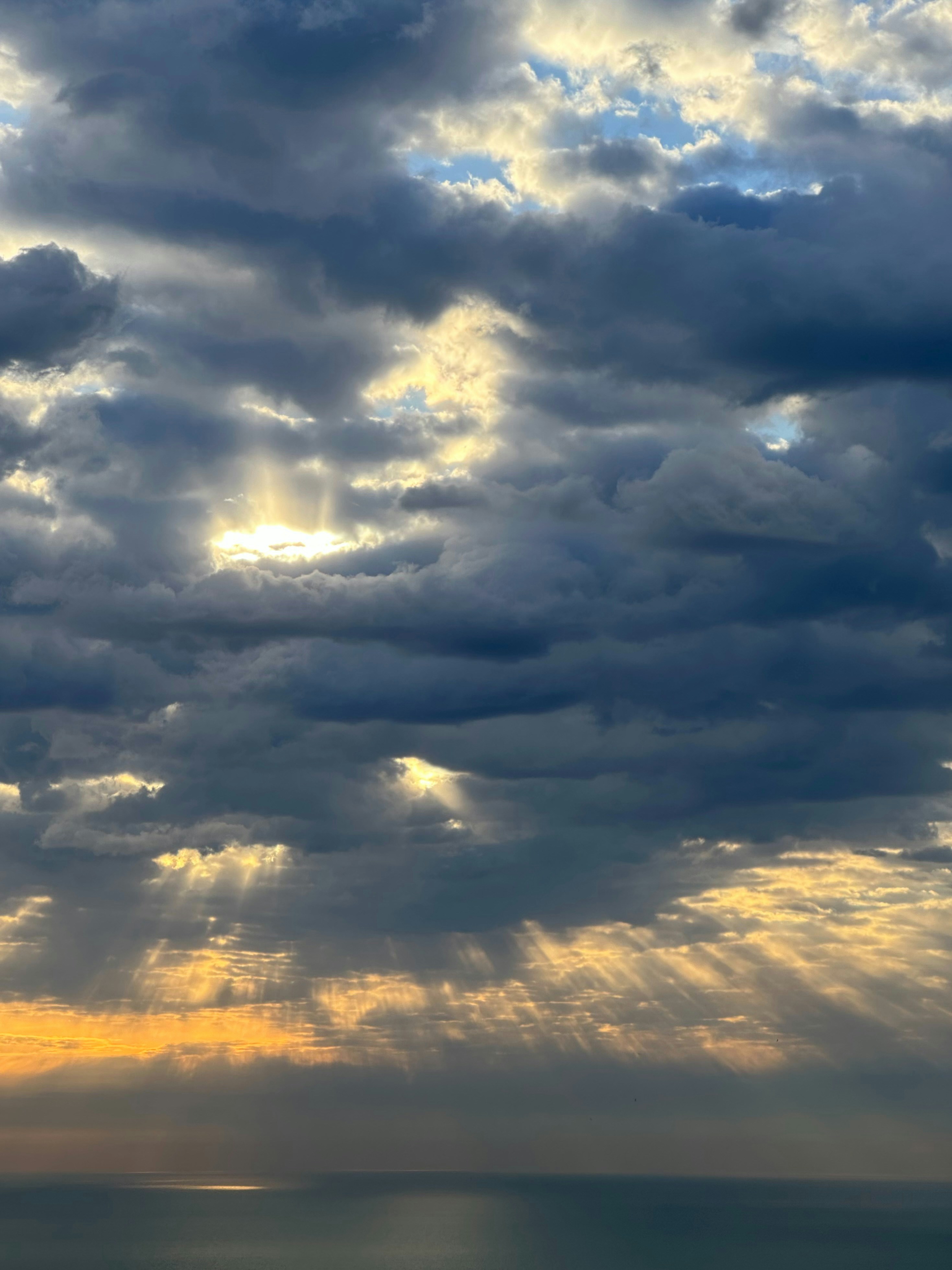 a plane flying through a cloudy sky over a body of water