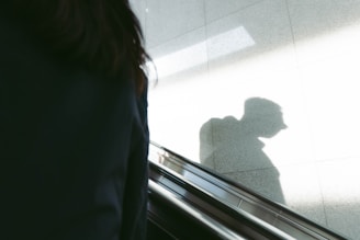 a shadow of a person on an escalator