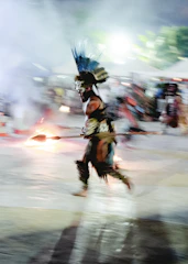 a man dressed in native american clothing running across a street