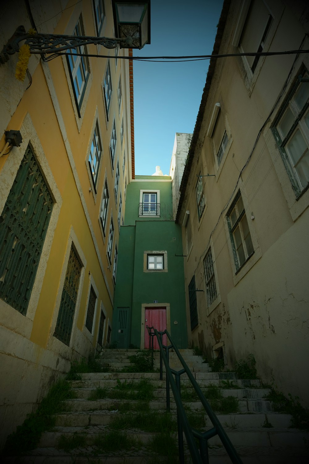 a green building with a red door and stairs