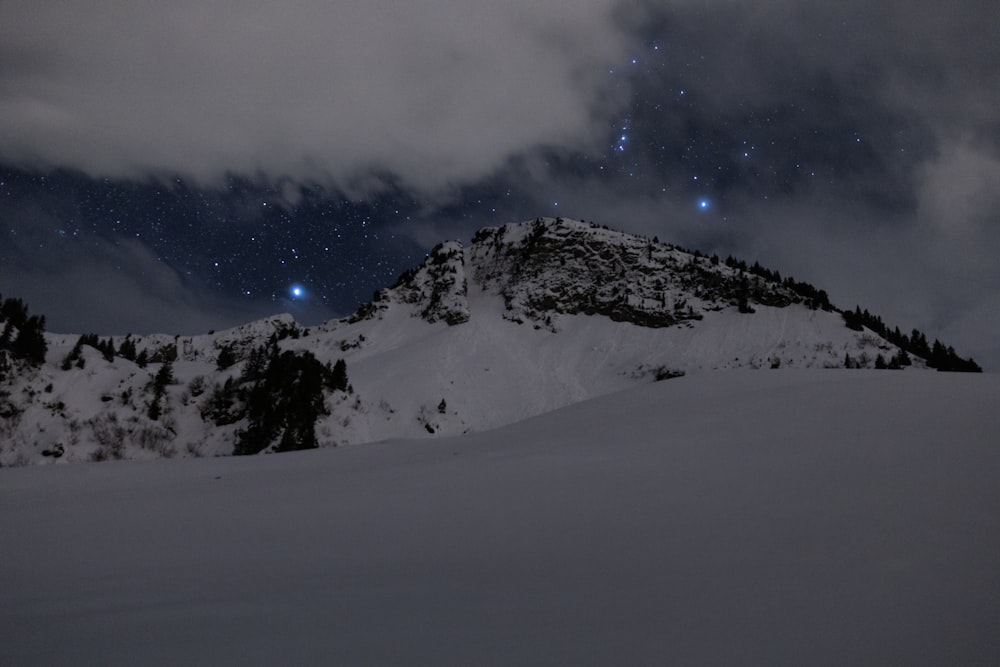 a mountain covered in snow under a cloudy sky