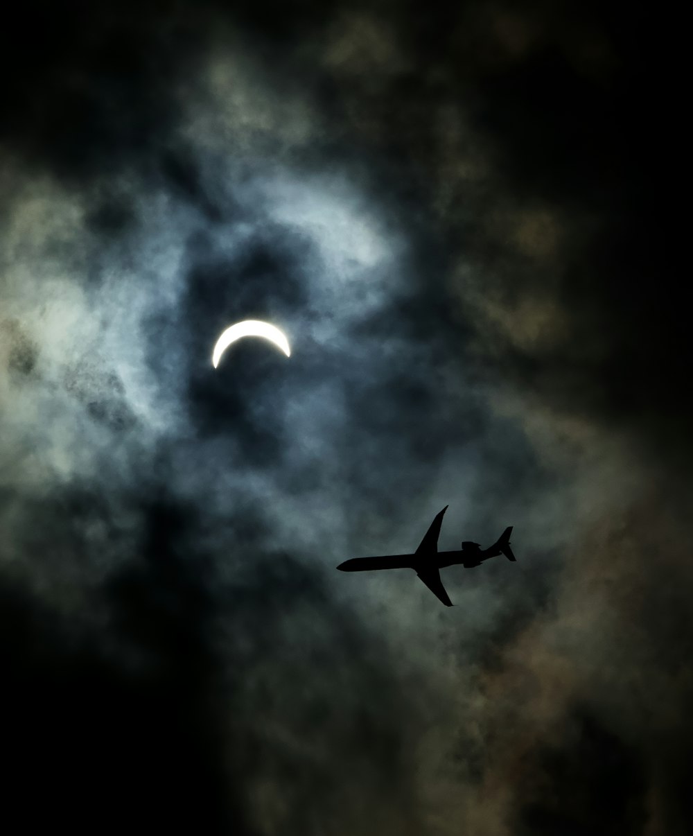 a plane flying in front of the moon