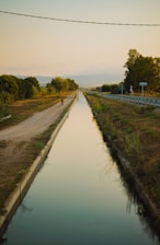 a man walking down a road next to a river