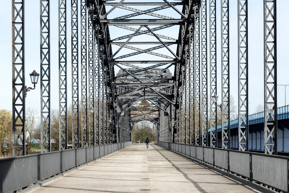 a man walking across a bridge over a river