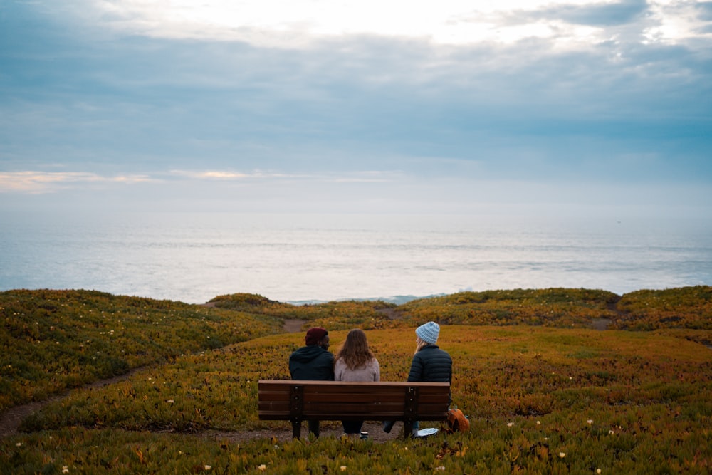 a couple of people sitting on top of a wooden bench