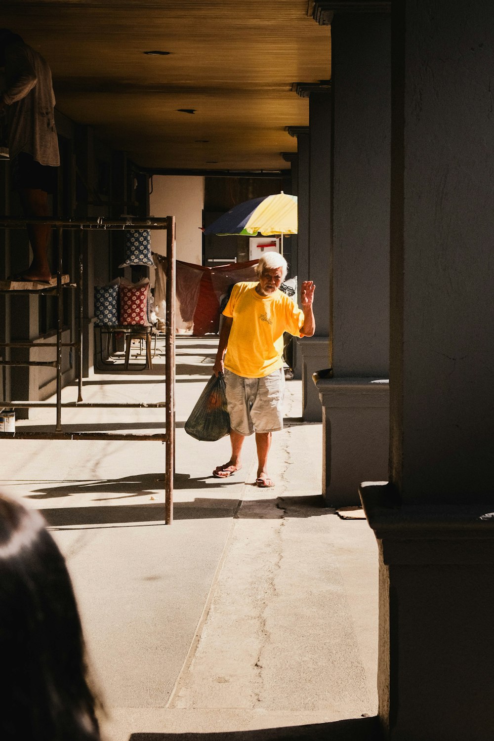 a man walking down a sidewalk holding an umbrella