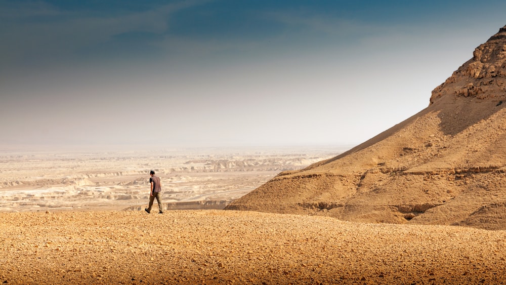 a man standing on top of a sandy hill
