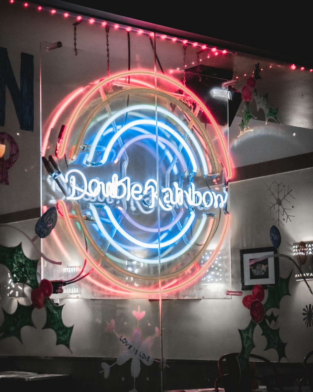 a neon sign that reads double rainbow hangs from the side of a building