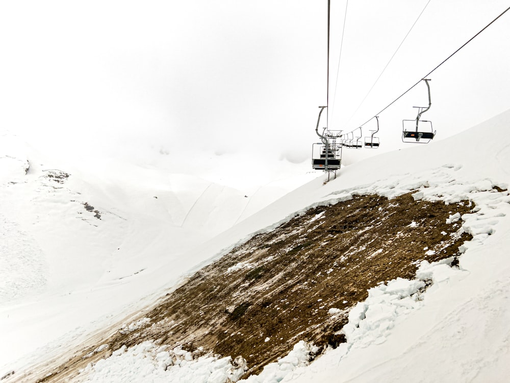 um teleférico subindo o lado de uma montanha coberta de neve