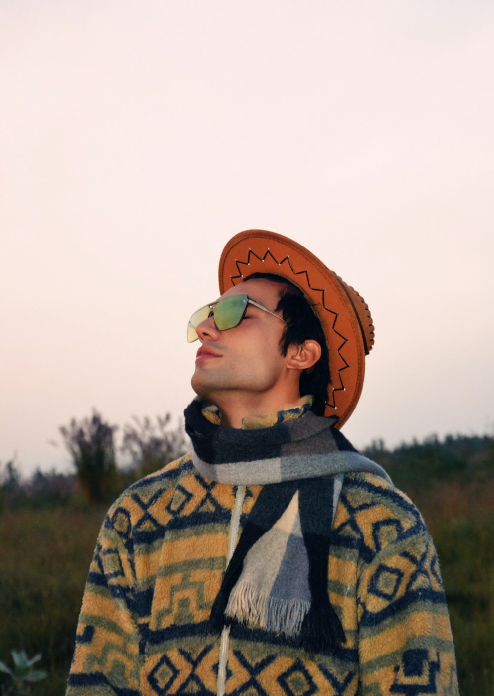 a man wearing a hat and scarf in a field