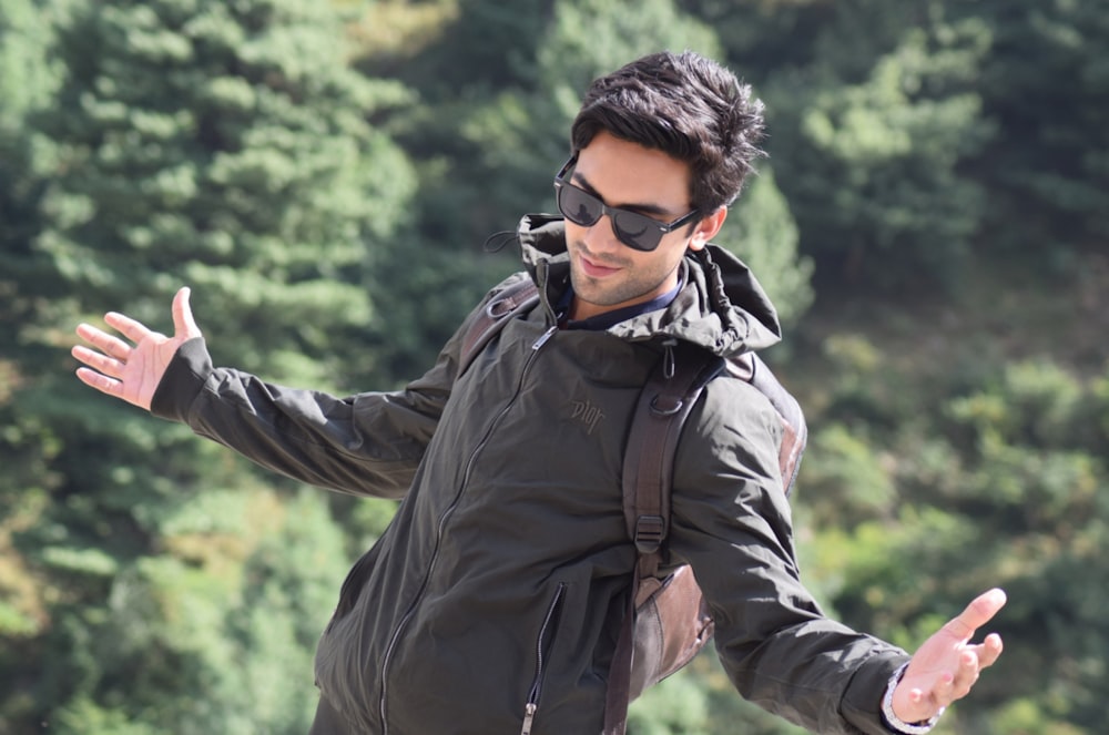 a man in a black jacket and sunglasses throwing a frisbee