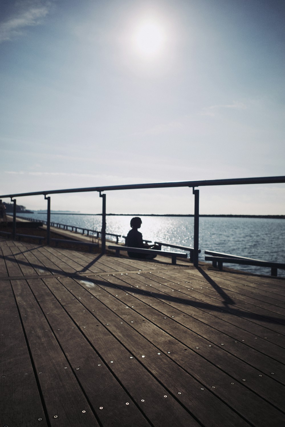 a person sitting on a bench on a pier