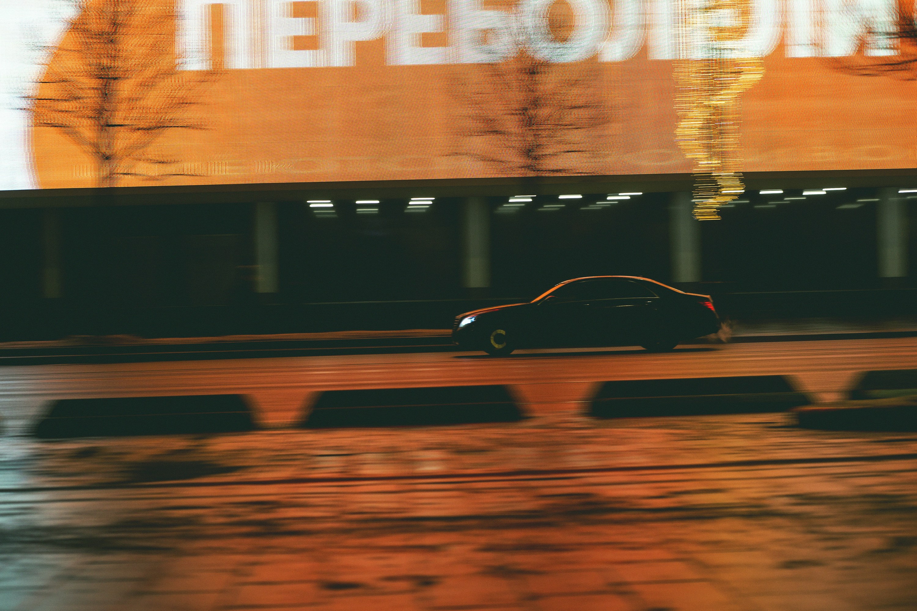 a car driving down a street next to a tall building