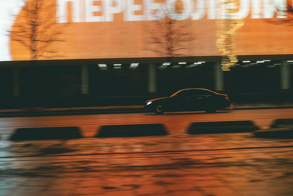 a car driving down a street next to a tall building