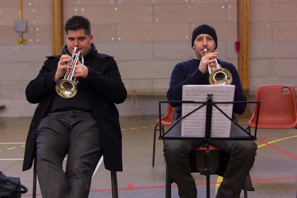 a couple of men sitting next to each other playing musical instruments