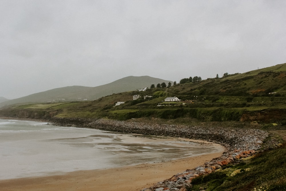 a view of a beach with houses on a hill in the background