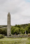 a tall stone tower sitting in the middle of a lush green field