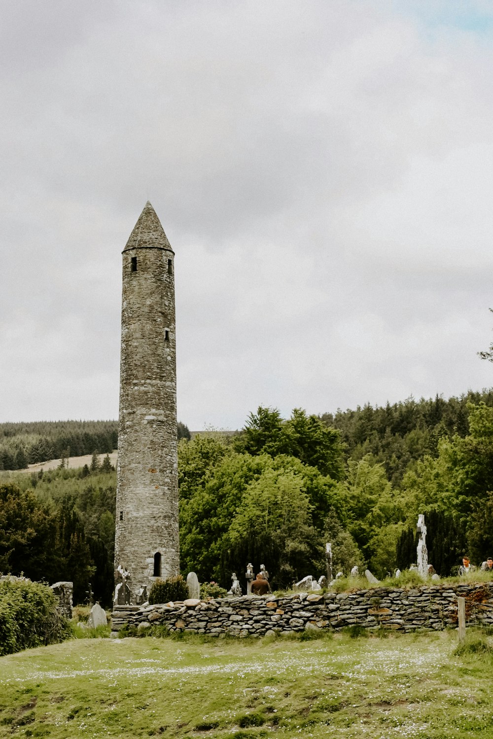 a tall stone tower sitting in the middle of a lush green field