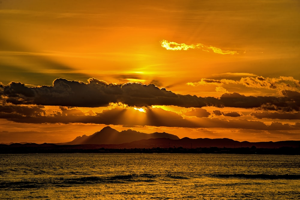 the sun is shining through the clouds over the water