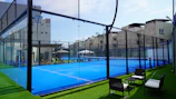 a tennis court with chairs and tables on the grass