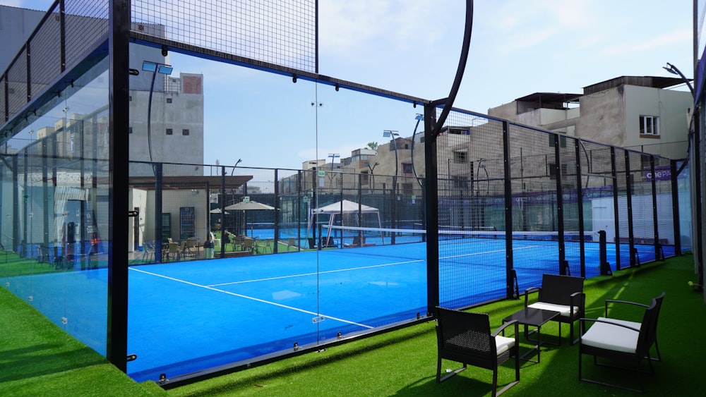 a tennis court with chairs and tables on the grass
