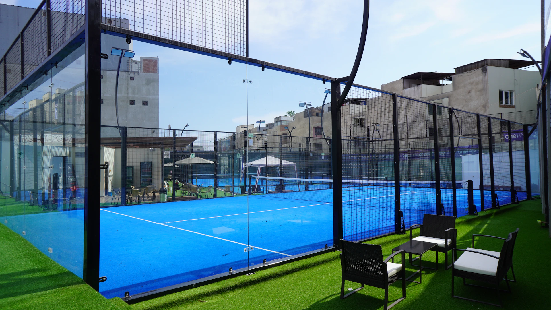 a tennis court with chairs and tables on the grass
