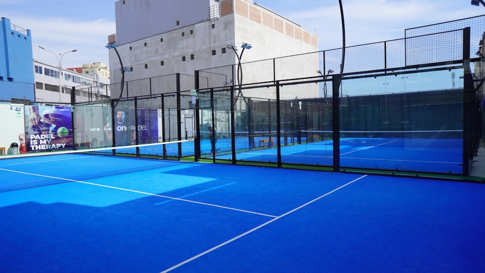 a tennis court with a blue tennis court and buildings in the background