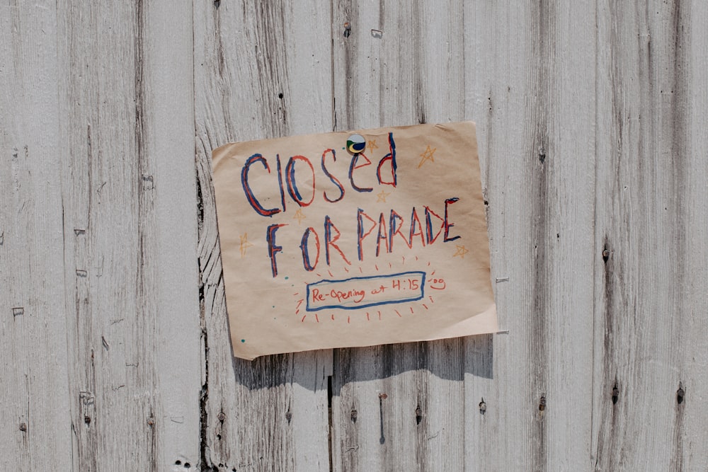 une pancarte affichée sur une clôture en bois indiquant qu’il est fermé pour le défilé ;