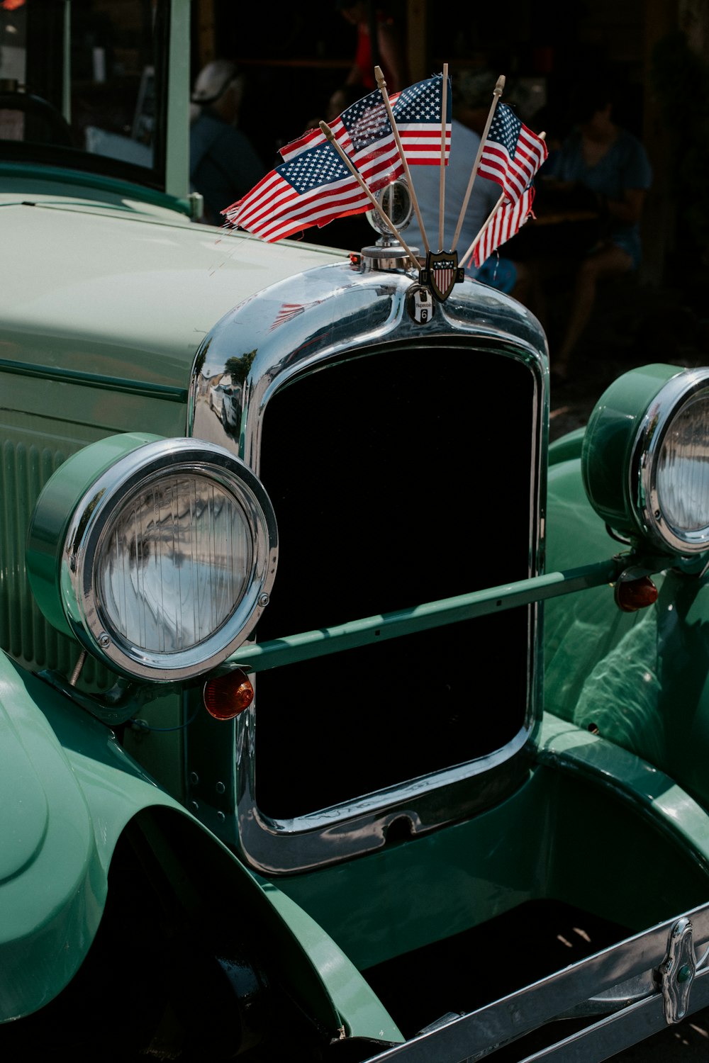 an old green car with american flags on it