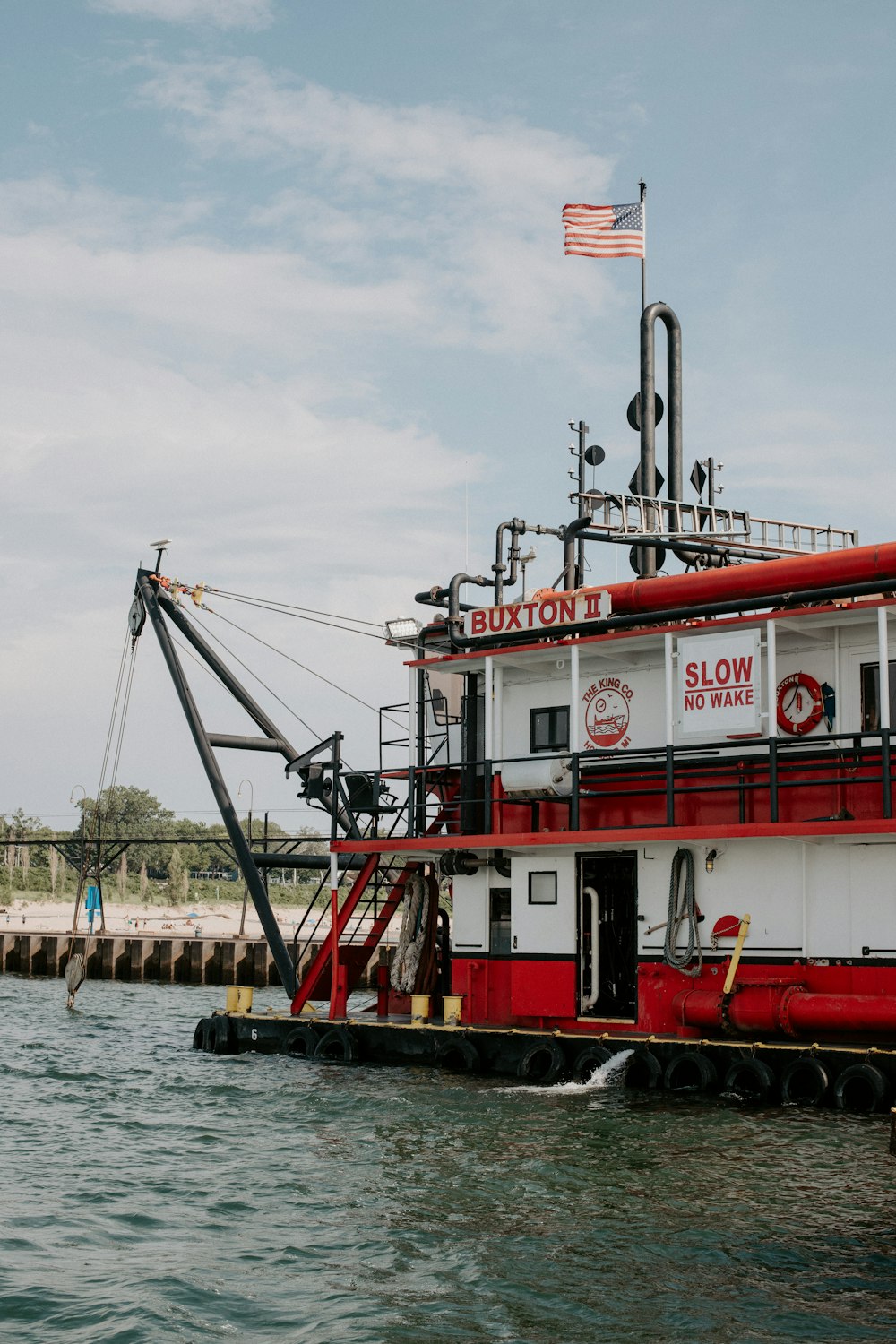 a red and white boat floating on top of a body of water