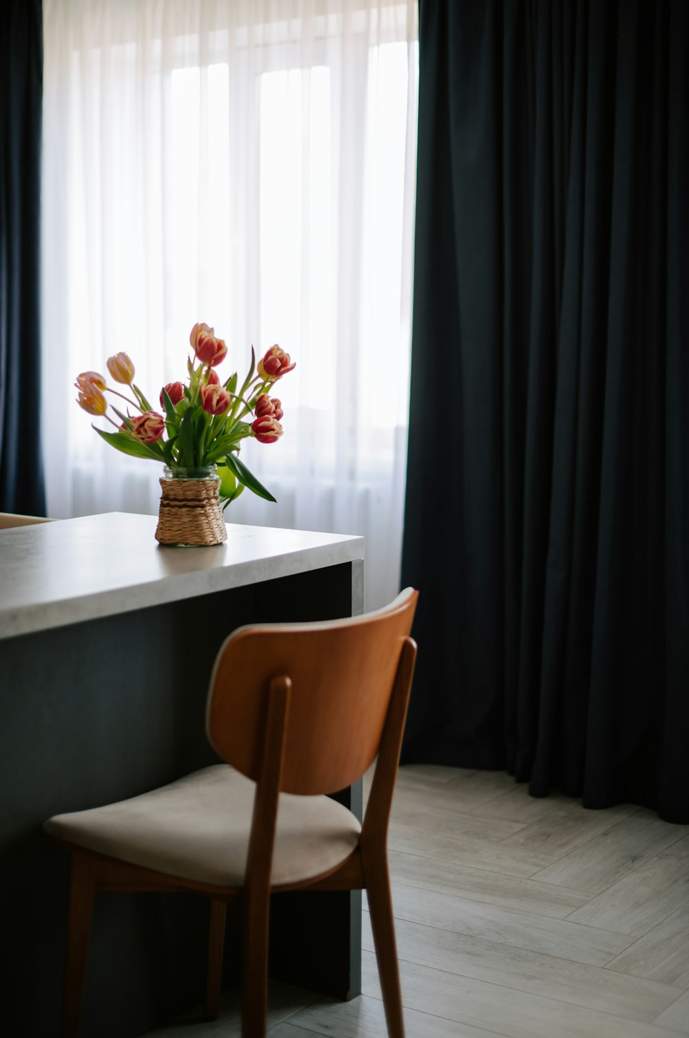 Un vase de tulipes est posé sur un comptoir à côté d’une chaise