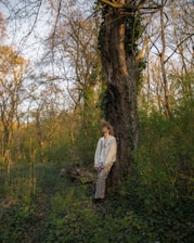 a man standing next to a tree in a forest