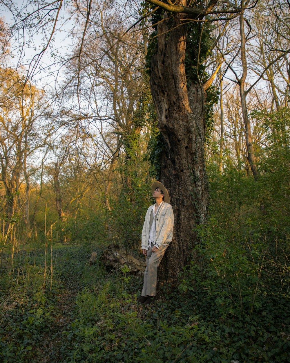 a man standing next to a tree in a forest