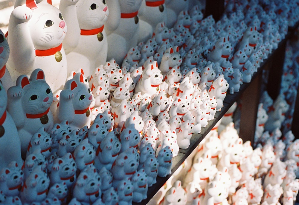 a bunch of small white and red cat figurines