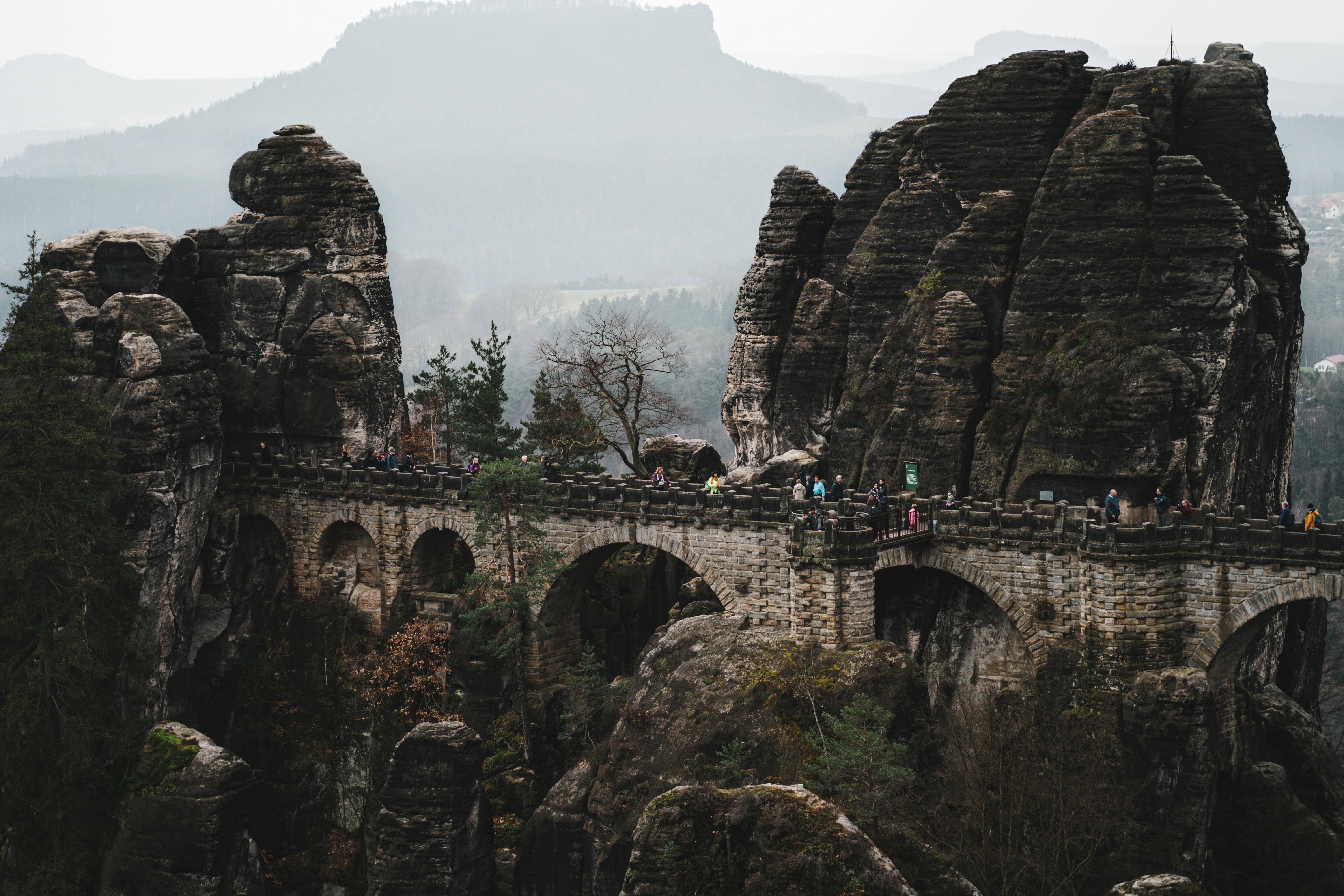a group of people standing on top of a stone bridge