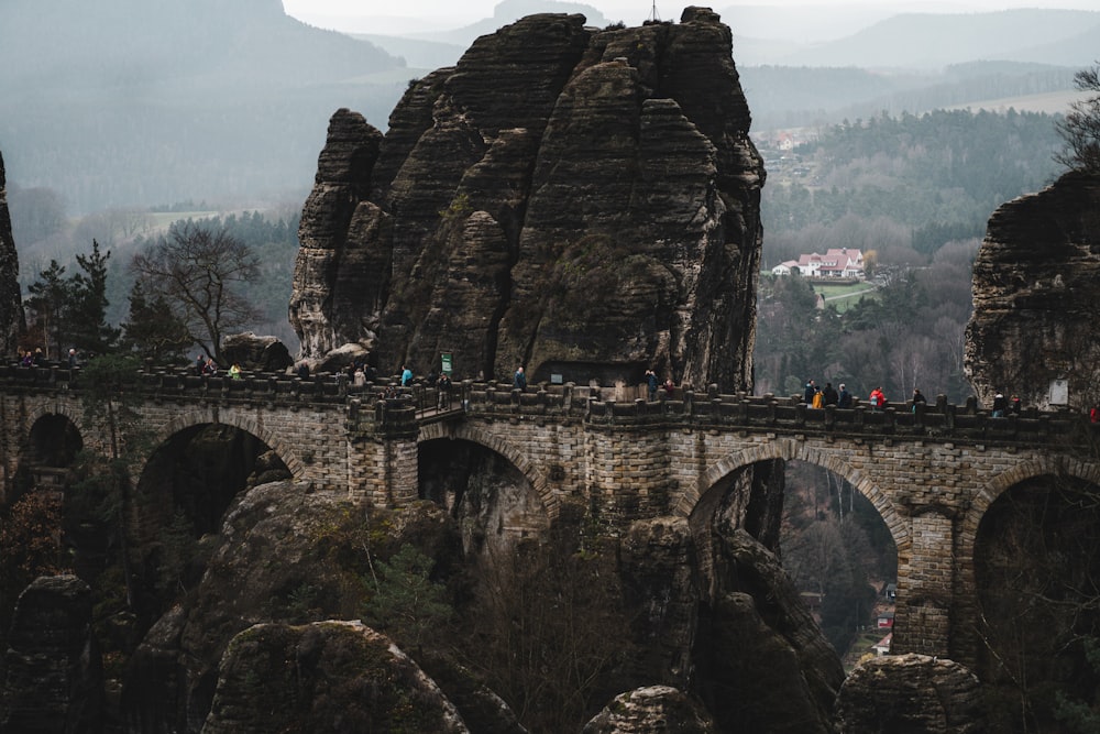 a group of people standing on top of a stone bridge