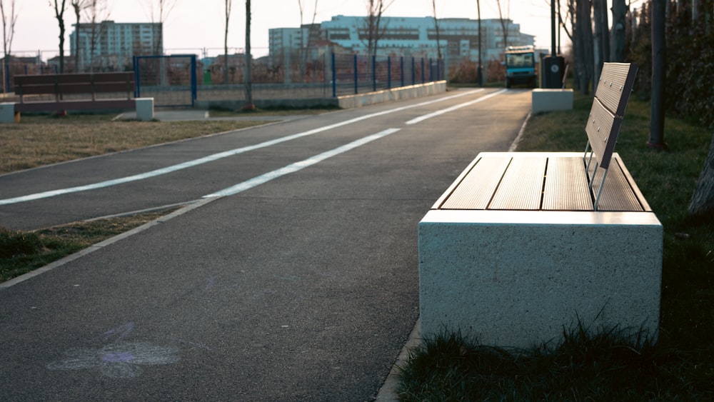 a wooden bench sitting on the side of a road
