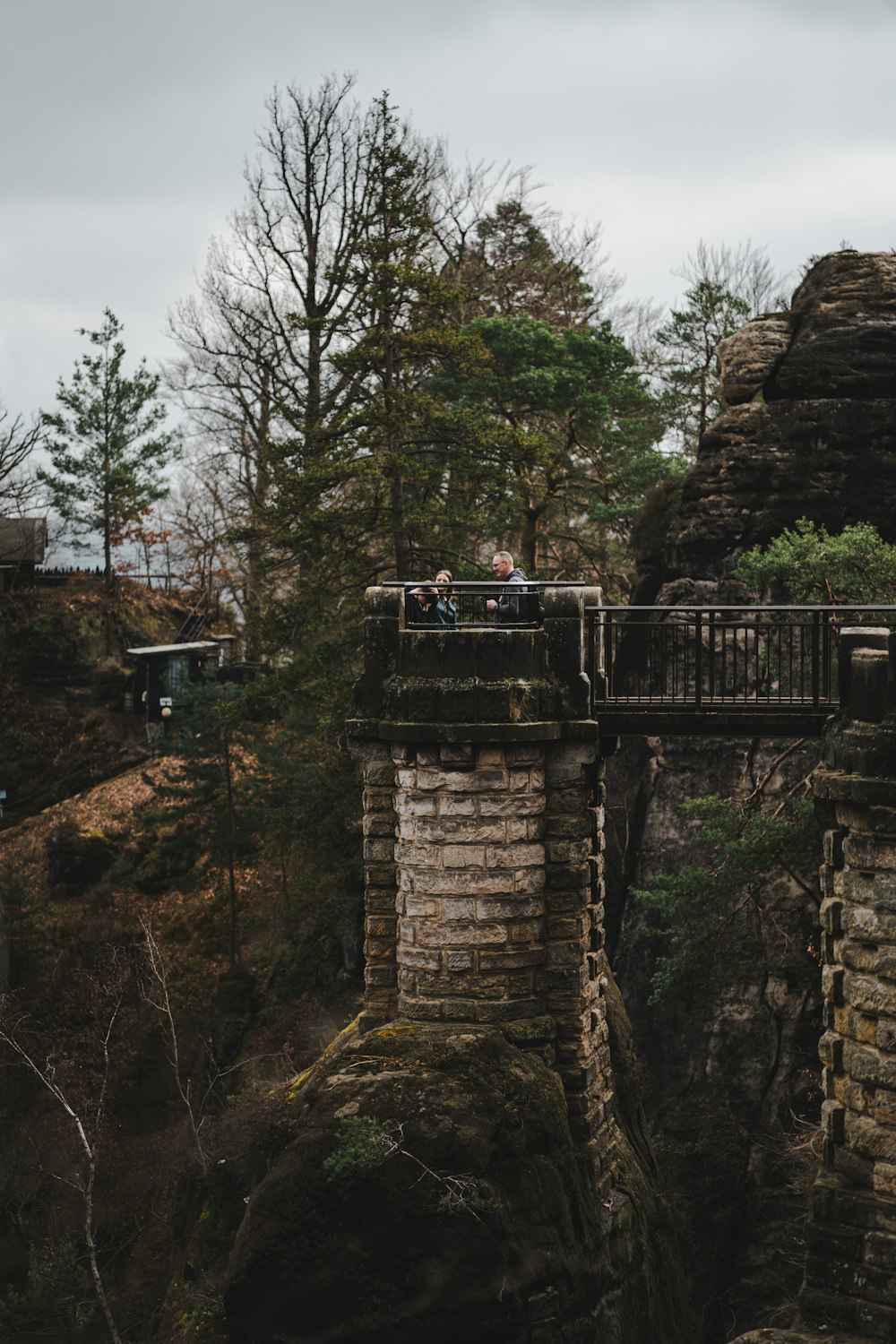 a couple of people standing on top of a bridge