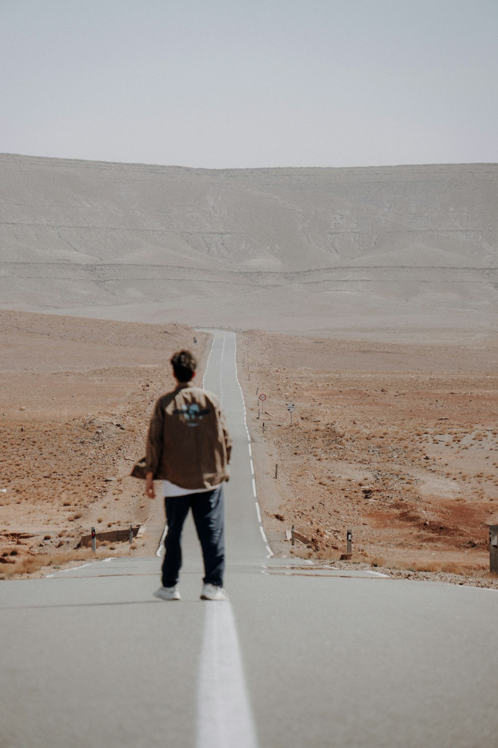 a man walking down a road in the middle of nowhere