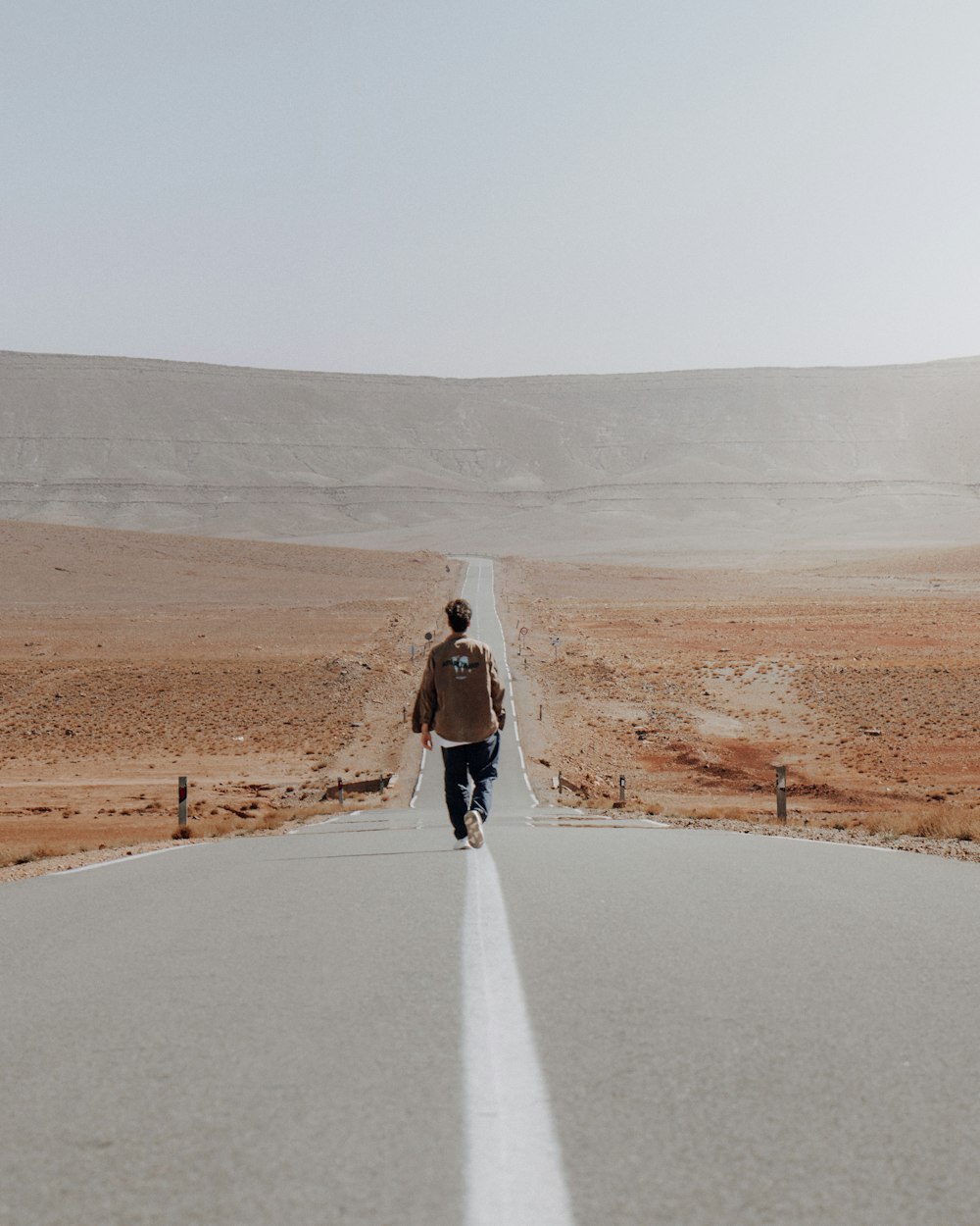 um homem caminhando pelo meio de uma estrada