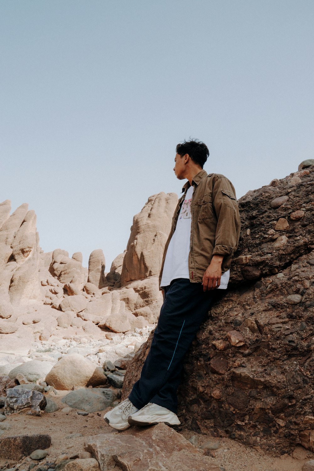 un hombre apoyado contra una roca en el desierto