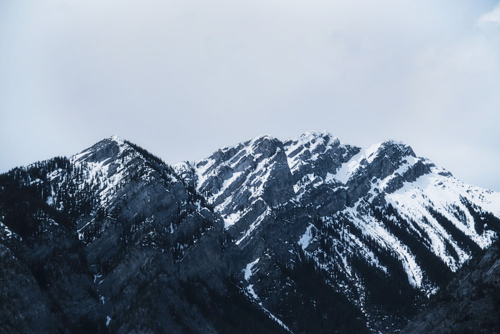 a mountain range covered in snow under a cloudy sky