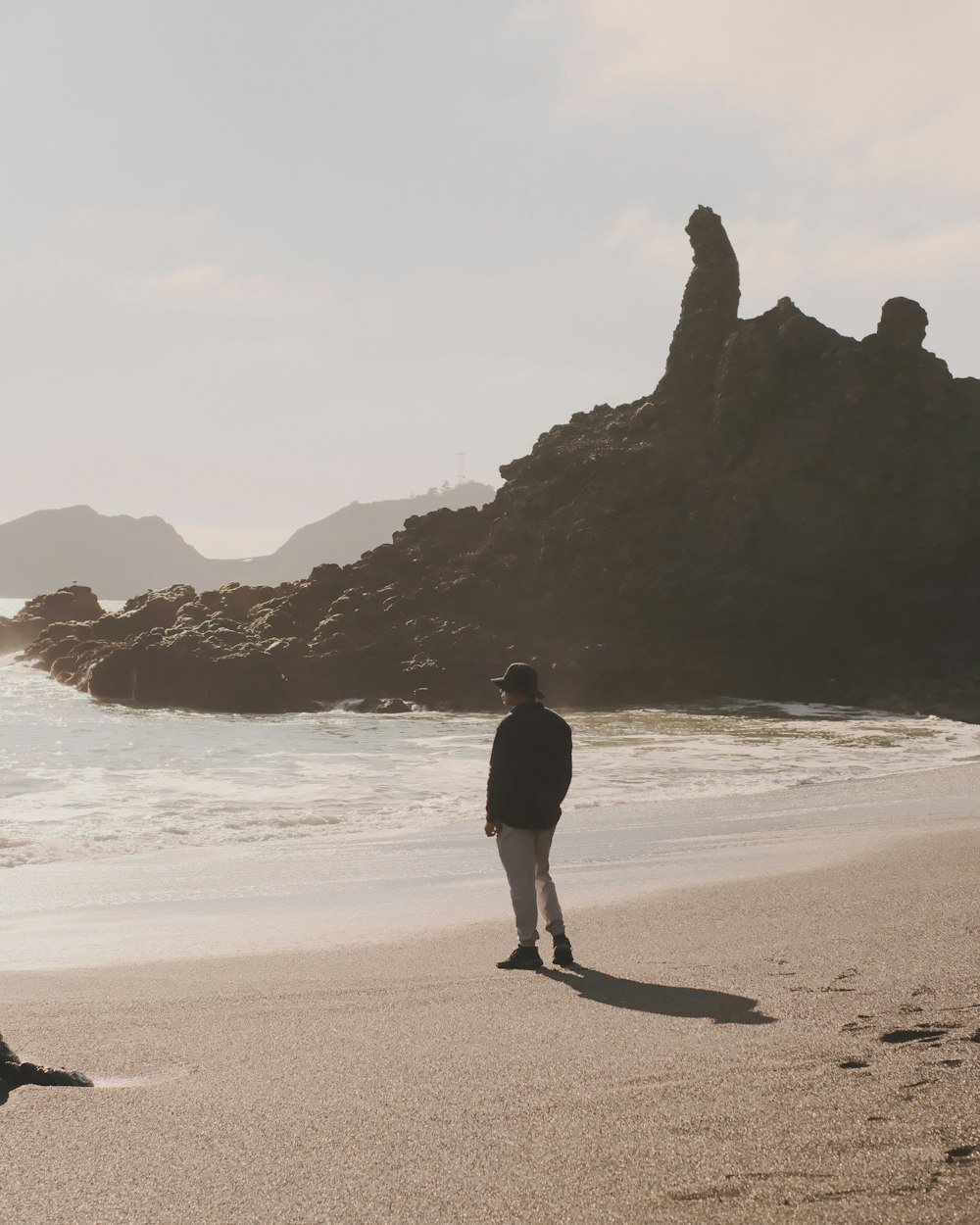 un uomo in piedi in cima a una spiaggia sabbiosa vicino all'oceano