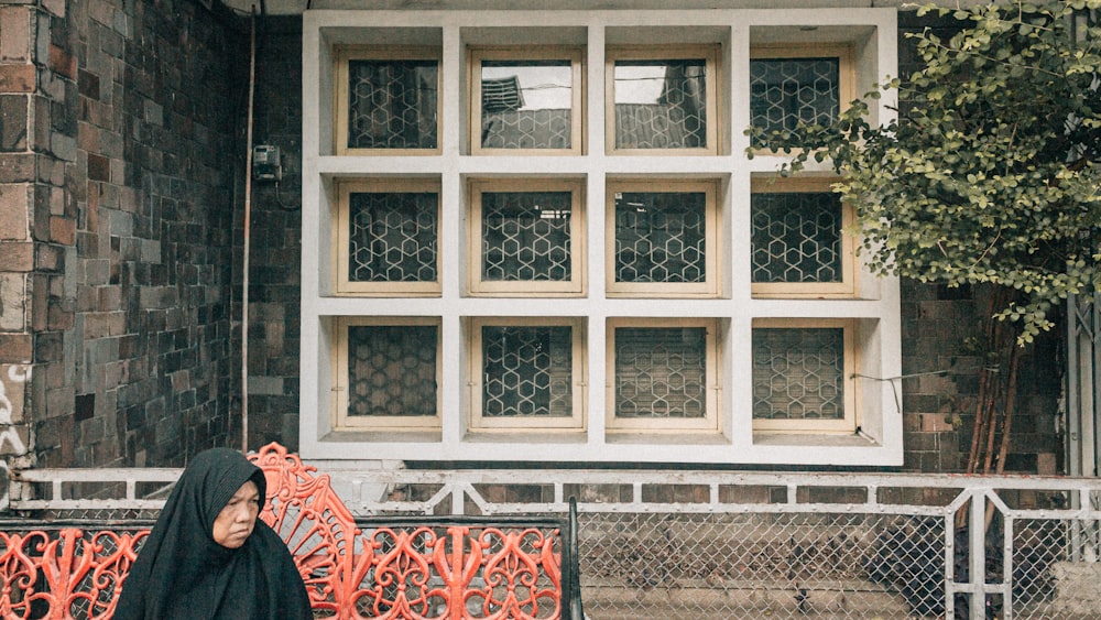 a woman sitting on a bench in front of a building