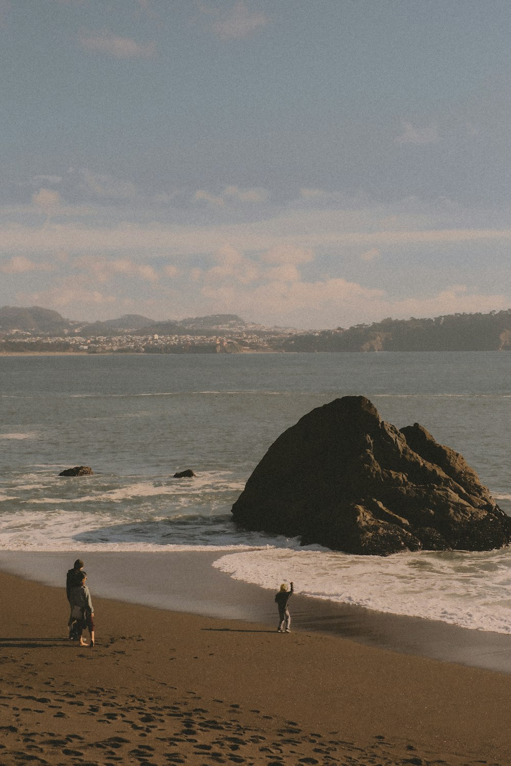 a couple of people standing on top of a sandy beach