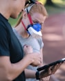 a man and a woman with a breathing mask on looking at a tablet