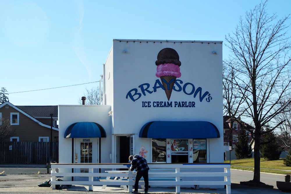 a man standing in front of a ice cream parlor