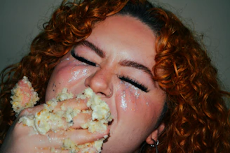A woman with red curly hair eating food